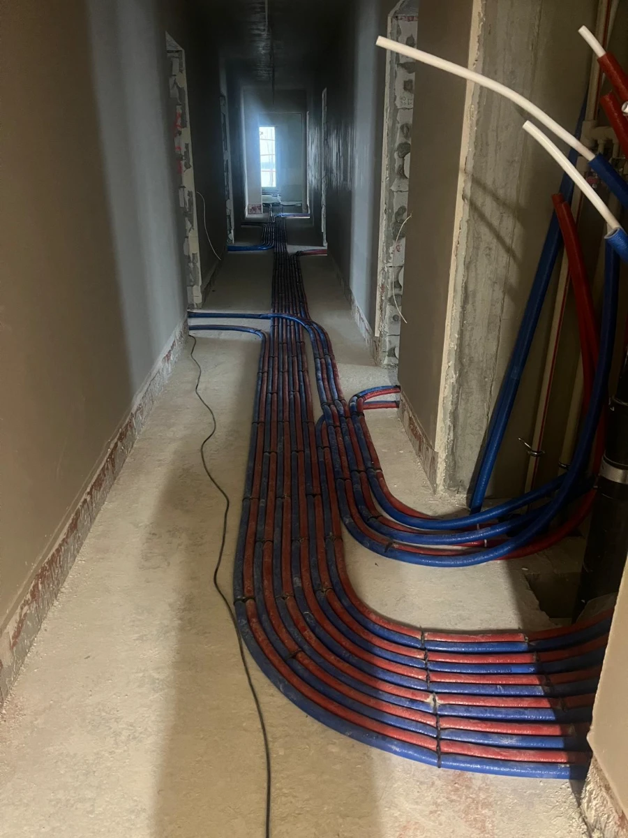 Instalacja ogrzewania podłogowego z wieloma rurami PEX ułożonymi w korytarzu