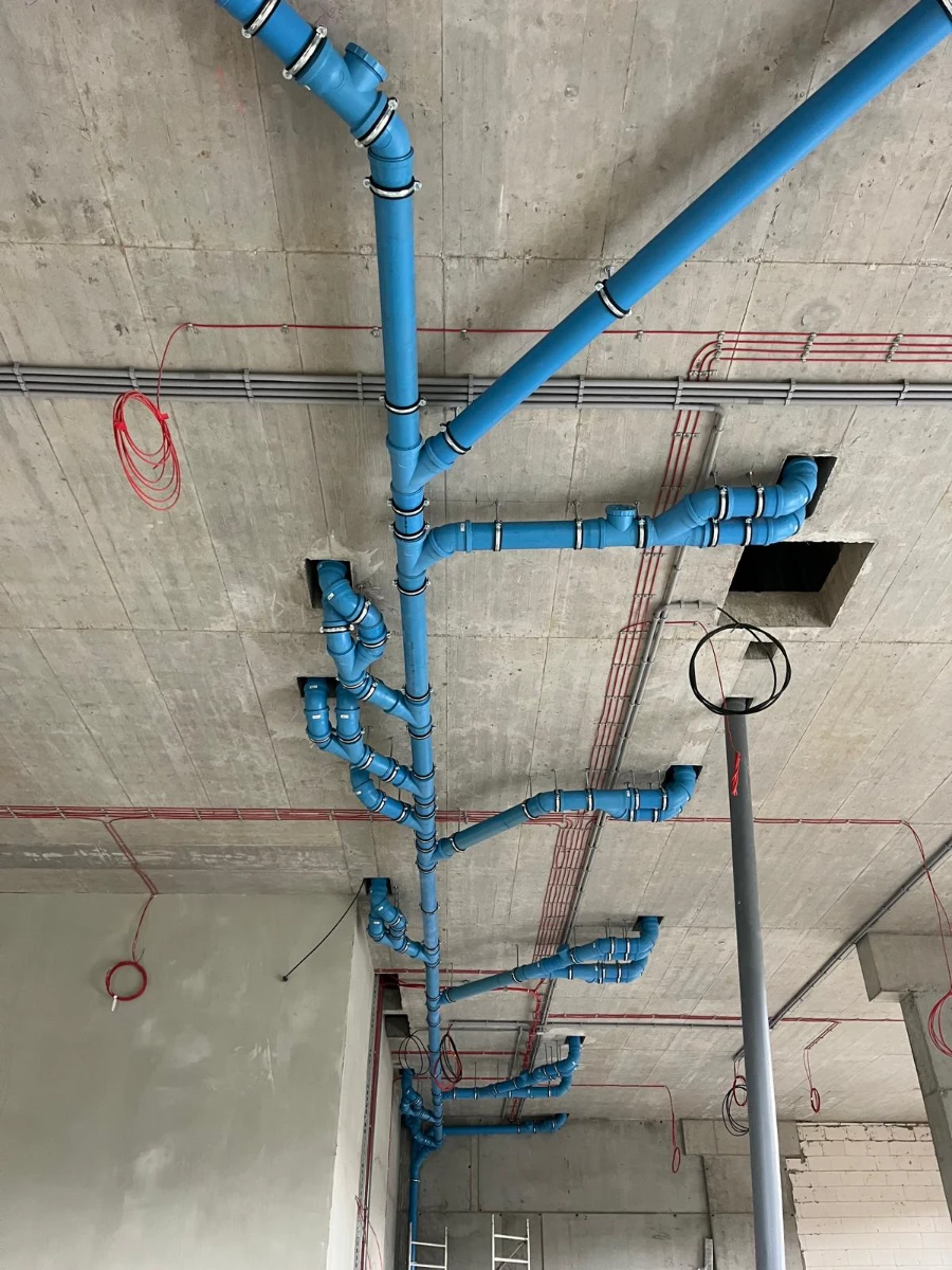 Montaż podstropowych niebieskich rur złączonych kolankami – instalacje sanitarne